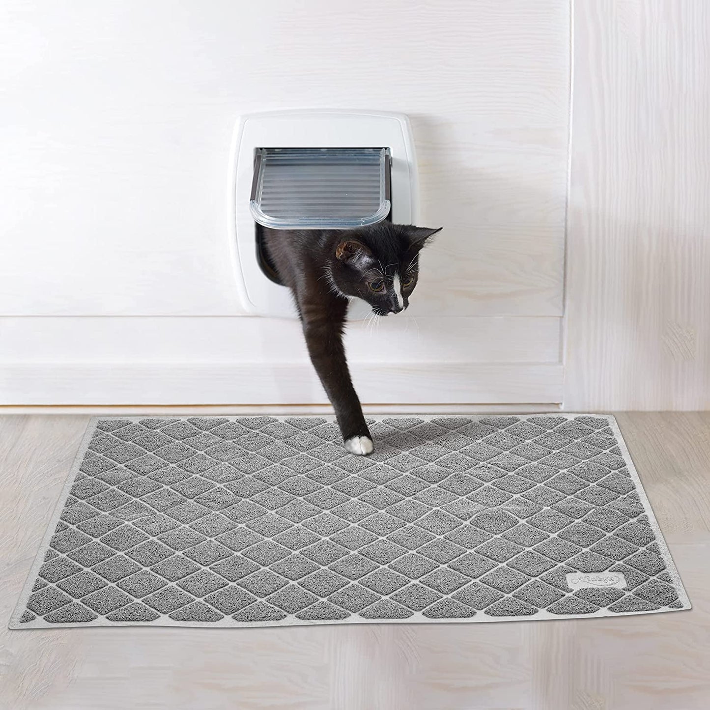 kat komt uit kattenluik en stapt op antislipmat