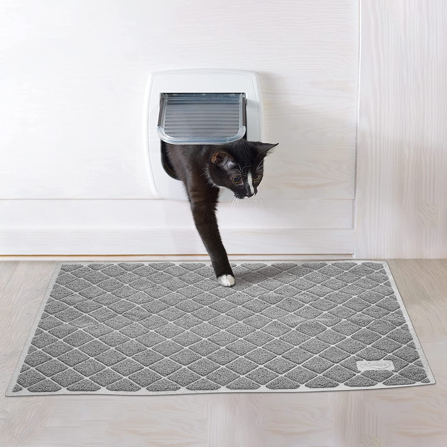 kat komt uit kattenluik en stapt op antislipmat